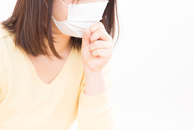 マスクをした女性が口に手を当て咳をしてる様子
